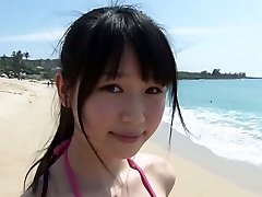 Slender Japanese girl Tsukasa Arai walks on a sandy beach under the sun
