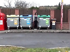 A bit plump amateur brunette gal squats down and pisses between refuse bins