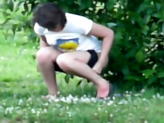 Young brunette with sexy legs pissing in the bushes