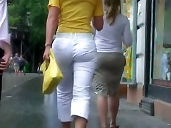 Elegancka blondynka na obcasach i w białych spodniach na ulicy szczery widok