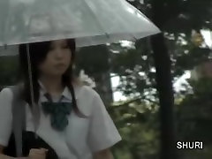 Asiatische Schulmädchen bekommt street sharking an einem regnerischen Tag