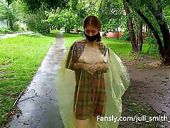 लड़की में एक बरसाती चमकती स्तन और गधा शहर की सड़कों पर