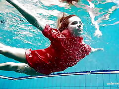可爱的女孩在红色性感的开放式礼服游泳