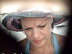 Mature white female in blue bathing suit pisses in the public toilet room on the beach