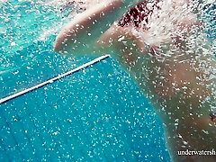 Petite bodied Nina Mohnatka swimming naked in a pool